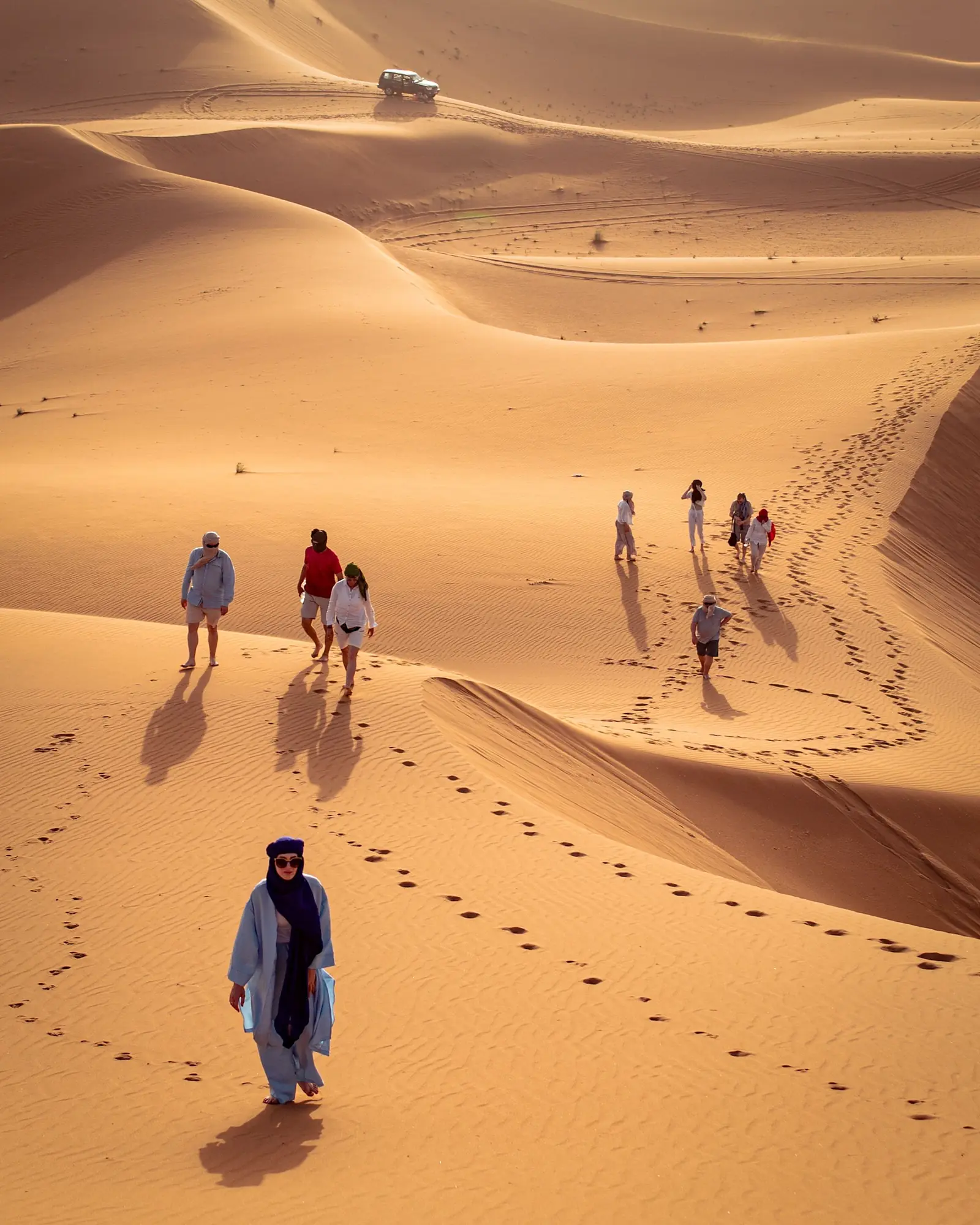 A small group of travellers walking the Erg Chebbi dunes with their guide