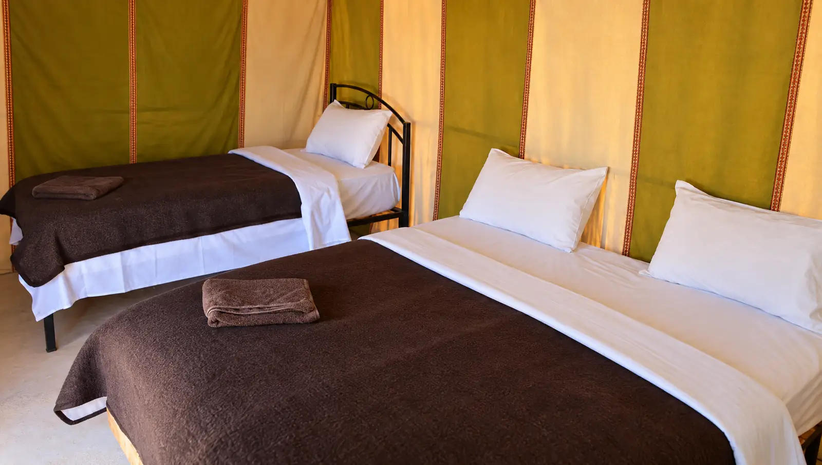A standard tent with a double bed and a single bed at Merzouga Standard Tents